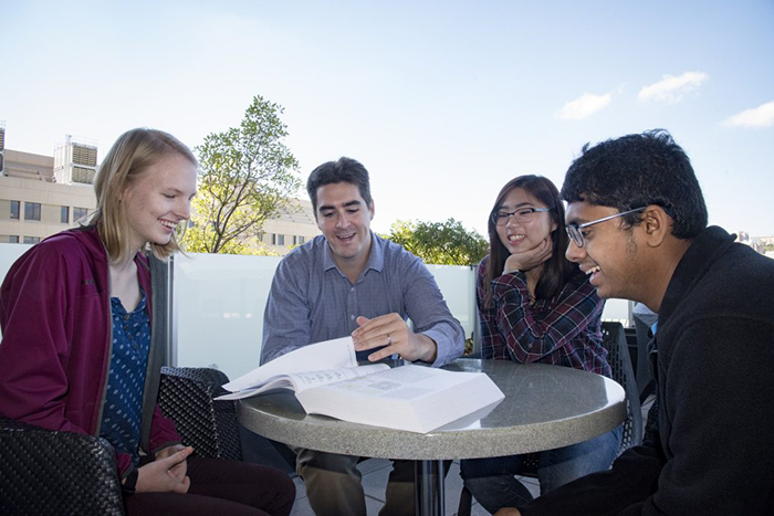 Computational biology students study with professor at table