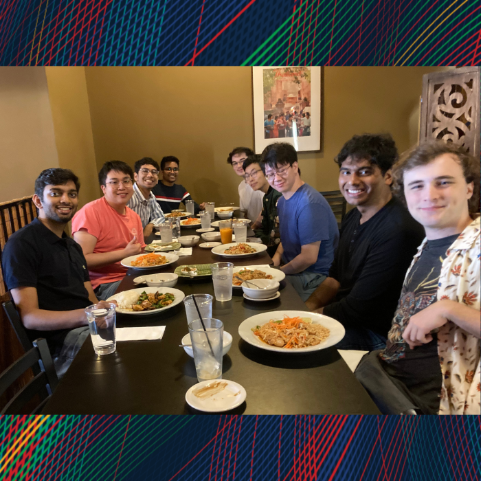 A group of students sitting around a table smiling for the camera
