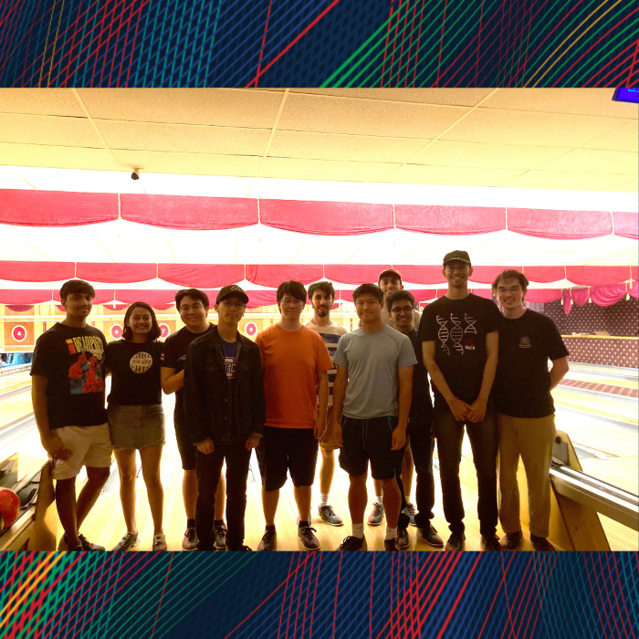 A group poses for a photo in front of bowling lanes