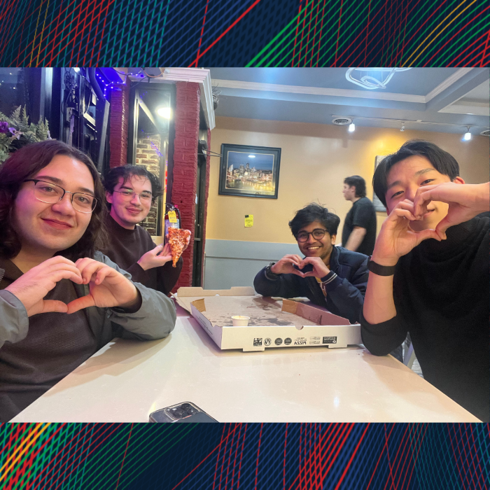 A group posing around a table makes a heart shape with their hands