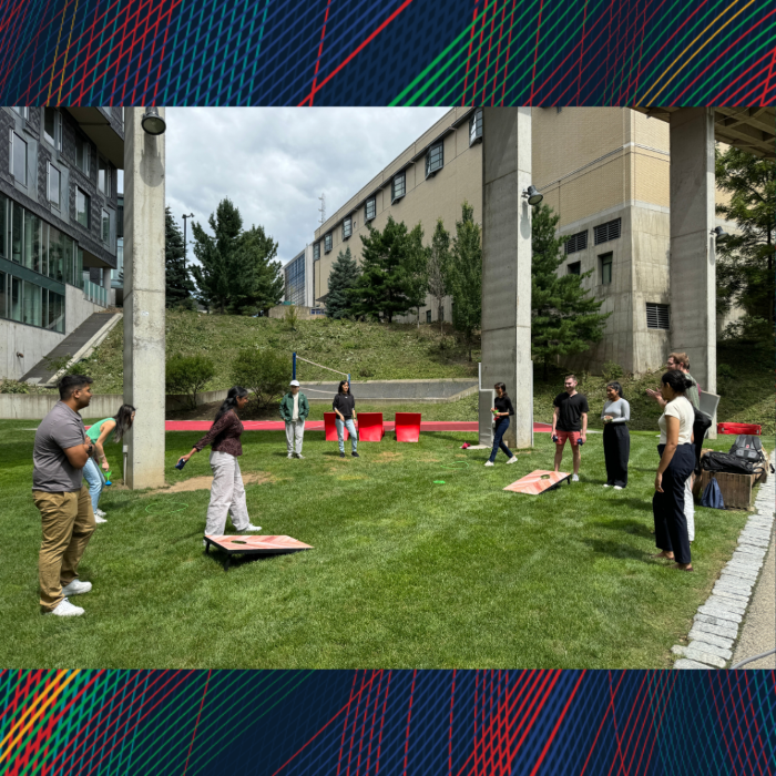 A group of men and women standing in the grass playing a lawn game