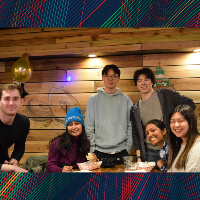 A group poses for the camera in front of a wooden backdrop