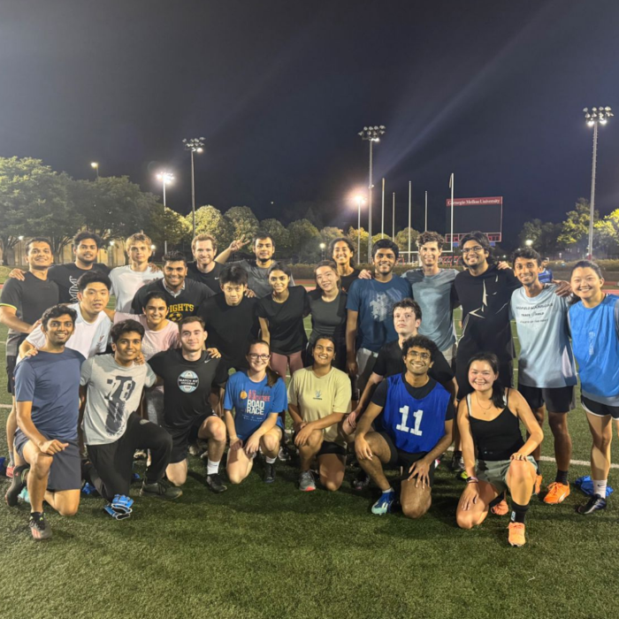 A group of people pose together on a football field after playing