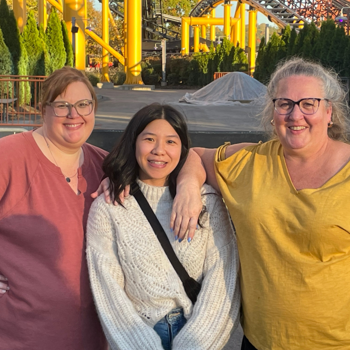 Three woman stand together, smiling for the camera