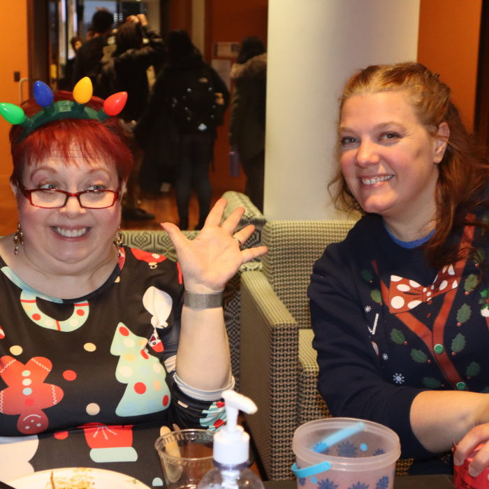 Two women dressed in festive shirts pose for the camera